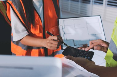 Endüstriyel mühendislerden oluşan bir ekip, fabrikadaki masada bulunan makine planlarını analiz ediyor. Fabrikada ya da üretim tesisinde çalışıyorum..