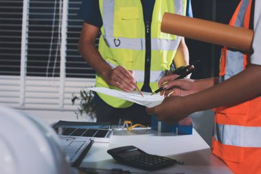 Endüstriyel mühendislerden oluşan bir ekip, fabrikadaki masada bulunan makine planlarını analiz ediyor. Fabrikada ya da üretim tesisinde çalışıyorum..