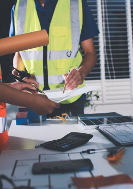Endüstriyel mühendislerden oluşan bir ekip, fabrikadaki masada bulunan makine planlarını analiz ediyor. Fabrikada ya da üretim tesisinde çalışıyorum..
