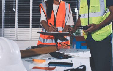 Endüstriyel mühendislerden oluşan bir ekip, fabrikadaki masada bulunan makine planlarını analiz ediyor. Fabrikada ya da üretim tesisinde çalışıyorum..