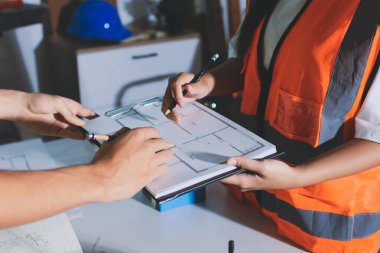 Endüstriyel mühendislerden oluşan bir ekip, fabrikadaki masada bulunan makine planlarını analiz ediyor. Fabrikada ya da üretim tesisinde çalışıyorum..