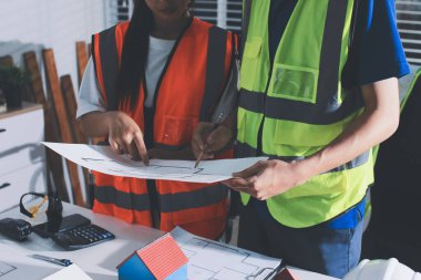Endüstriyel mühendislerden oluşan bir ekip, fabrikadaki masada bulunan makine planlarını analiz ediyor. Fabrikada ya da üretim tesisinde çalışıyorum..