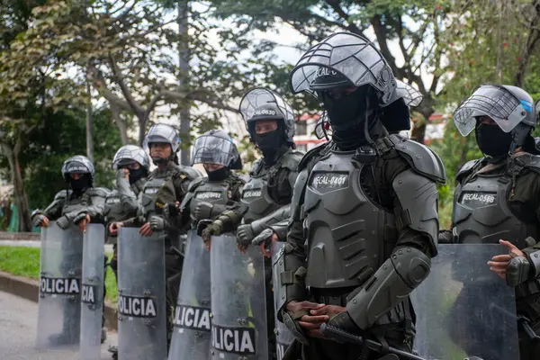 Yazı işleri, Kolombiya UNDEMO çevik kuvvet biriminin üyelerini koruyucu miğferler, kalkanlar ve çelik yelek de dahil olmak üzere tam bir isyan karşıtı teçhizatla gösteriyor. Memurlar kamuya açık bir şekilde konuşlandırıldılar.