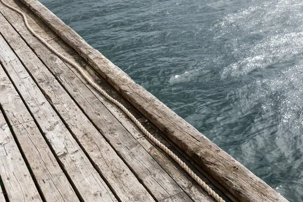 Norveç 'te fiyortlu ahşap iskele. Yıpranmış kalaslar ve berrak sudaki hafif dalgalar bu İskandinav kıyı sahnesinde sakin bir deniz atmosferi yaratır..