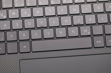 Hafif açılı makro fotoğraf yeni gri dizüstü bilgisayarın klavyesi uzay çubuğu ve touchpad 'in bir kısmını gösteriyor, stüdyo açık ışık ve keskin detaylarla çekiliyor..