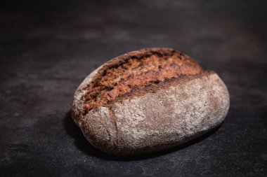 Koyu yüzeyde yükselen kabuklu ev yapımı ekşi ekmeğin yakın plan yan görüntüsü