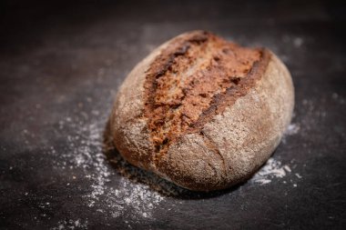 Yakın plan ev yapımı ekşi ekmeğin koyu yüzeye yükselen kabuğu un serpiştirilmiş hali.