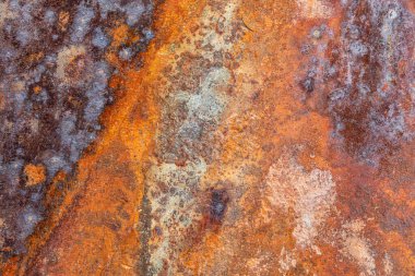 Aşırı paslanmış demir yüzeyin yakın çekimi, yoğun aşınmayla birlikte, turuncu ve kahverengi tonlarını gösteriyor, gelişmiş oksitlenme nedeniyle parlak turuncu yamalar da dahil.
