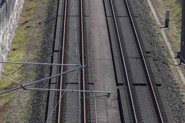 Her iki tarafında yeşil bitki örtüsü bulunan ve elektrik altyapısı ve raylarını gösteren modern çift demiryolu raylarının üstündeki tepeden aşağı bakan katenarizasyon sisteminin tepeden görünüşü