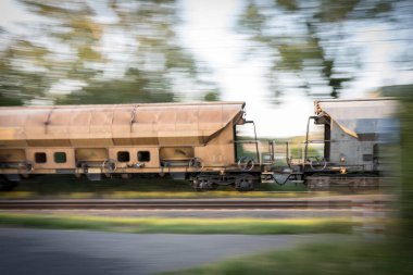 Yük vagonunun bulanık arka plan ve görünür raylarla birleşiminin görüntüsü, keskin tren ve hareket-bulanık ortamı göstermektedir.