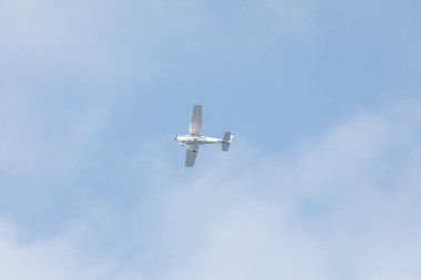 Mavi gökyüzüne doğru uçan beyaz tek motorlu özel uçak, yüksek kanatlı tasarımın kabinin üzerine monte edilmiş kanatları, açık hava ve görünür uçak detayları