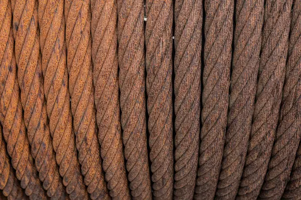 Terk edilmiş tersanedeki büyük makarada paslı metal kabloların yakın çekimi, aşınmanın detaylı dokusu ve yıpranmış metal görünür.