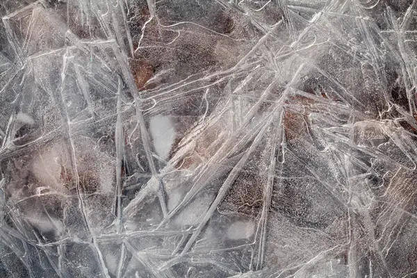 İnce buz tabakası, yukarıdan aşağıya makro görünüm detaylı kırık çizgileri ve doğal buzlu dokuyu gösteriyor.