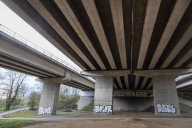 Karayolu köprüsünün altından görünen beton sütunlar ve küçük yol üzerindeki yapısal ayrıntılar  