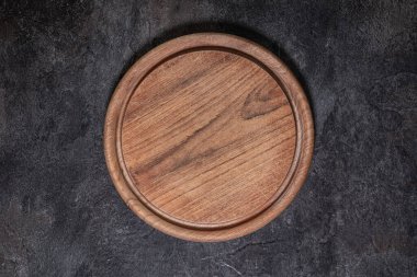 Kullanılmış yuvarlak tahta kesme tahtasının tepeden tırnağa yakın plan, üzerinde bıçak izleri var.