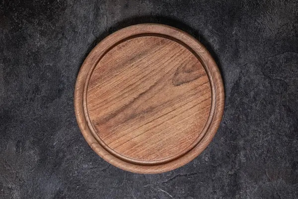 Kullanılmış yuvarlak tahta kesme tahtasının tepeden tırnağa yakın plan, üzerinde bıçak izleri var.