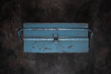 Koyu yüzeyde kapalı kaliteli mavi metal alet kutusu, hafifçe yükseltilmiş ön görüş, stüdyo aydınlatması, görünür araç veya arka plan elementleri yok