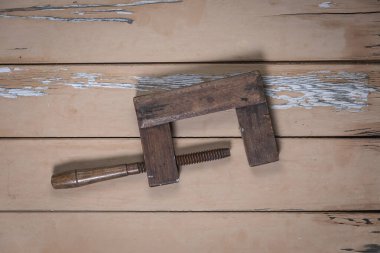 Eski ahşap kıskaç, eski bej bir masanın ortasına yerleştirilmiş, boyası soyulmuş, yukarıdan çekilmiş..