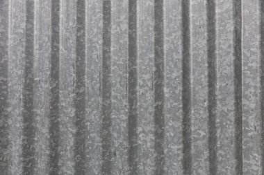 Arka plan olarak uygun dikey çizgileri olan yeni gri kıvrımlı metal levhanın yakın plan görüntüsü