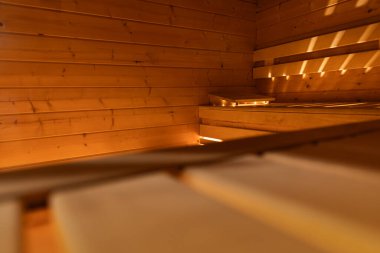 Ön planda yumuşak bulanıklık olan boş sauna manzarası ve ahşap bankta keskin bir odak ve ters tarafta arka planda ön plan tasarımı ve ahşap dokusu..  