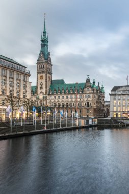 Kleine Alster Nehri 'ndeki Hamburg Belediyesi' nin gündüz fotoğrafı bulutlu gökyüzü ve tarihi binanın pürüzsüz su yansıması..  