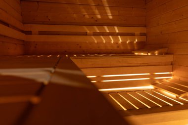 Boş sauna, ön taraftaki bankta odak dışı, sıcak ışık ahşap levhaların altında parlıyor.