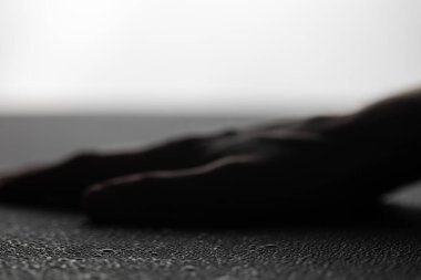 Karanlık el, parlak beyaz arka planda su damlacıklarıyla kaplı ıslak yüzeye dayanır.