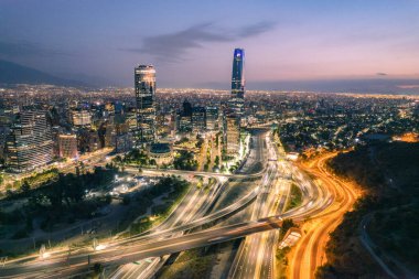 Santiago, Şili 'nin günbatımında hava görüntüsü Costanera Merkezi gökdeleni ve modern şehir gökyüzünü hareketli bir trafik ile gösteriyor.