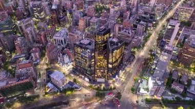 Santiago, Şili 16 Ekim 2024: İnsansız hava aracı alacakaranlıkta MUT binasına yaklaşıyor, Las Condes 'in finans bölgesinde yukarıdan canlı şehir ışıklarını ve kentsel ufuk çizgisini yakalıyor..