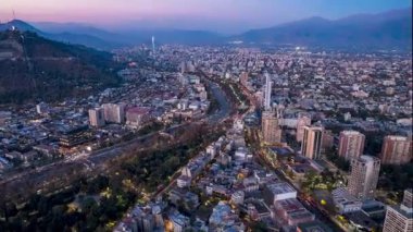 SANTIAGO, Şili Nisan, 18, 2024. İnsansız hava aracı Santiago Centro 'ya doğru ilerliyor, doğuya bakıyor. Şehir ışıklarını, kentsel yayılımı, Mapocho Nehri 'ni ve And Dağları' nı gün batımında yakalar. Canlı şehir manzarası.