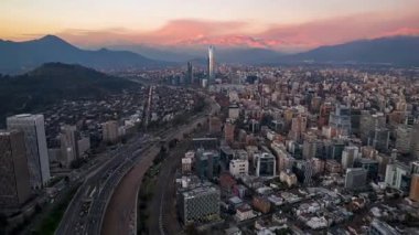 SANTIAGO, Şili AĞUSTOS, 24, 2023. Dinamik hiperhız: İHA Santiago 'ya doğru ilerliyor. Canlı gün batımını, Gran Torre Santiago 'yu, karmaşık otoyol kavşaklarını ve şehir ışıklarını yakalıyor. Simge görünümü