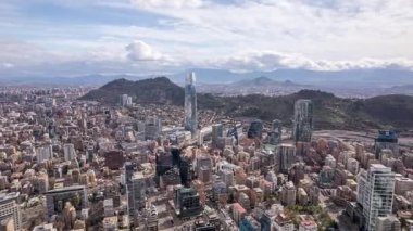 Noel Baba, Şili AĞUSTOS, 10, 2023. Dinamik hiperhız: İHA Santiago 'ya yandan yaklaşıyor. Gran Torre Santiago 'yu, geniş şehir manzarasını ve bulutlu gökyüzünün altındaki And Dağlarını yakalar. Simgesel hava görüntüsü