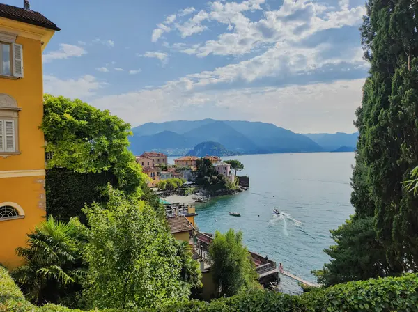 İtalya 'nın Como Gölü' nde, Varenna 'da renkli rıhtım binaları, tekneleri ve manzaralı dağ arka planlarıyla
