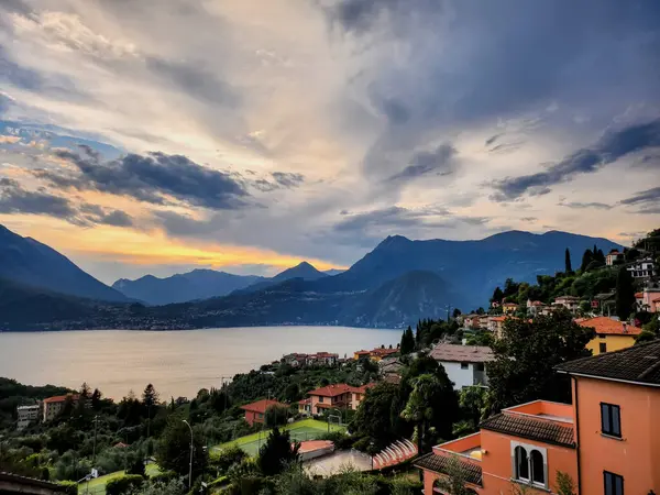 Perledo 'dan gün batımında Como Gölü manzarası, gölün karşısında Menaggio, Lombardy, İtalya' da Varenna 'da Como Gölü' nde tekneler ve manzaralı dağ manzaralı binalar.