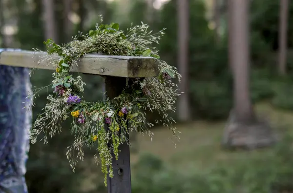 Bereketli bir ormanda ahşap bir direği süsleyen el yapımı bir çelenk yaz ortası geleneğini ve doğayı simgeliyor.