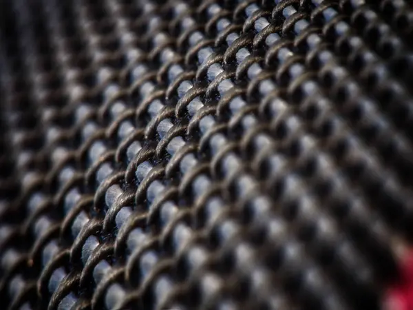 Metalik parıltılı ve tekrarlayan desenli örgü dokusunun detaylı bir yakın çekimi.