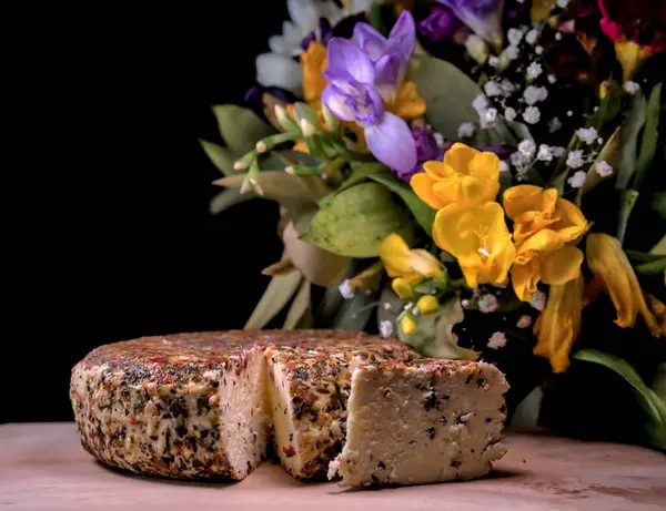 Arka planda çiçekler olan ahşap tabakta geleneksel Letonya peyniri