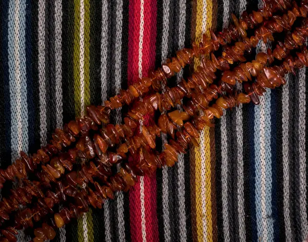 Kehribar boncuklar renkli yün kumaş üzerinde çapraz hizalanmış.