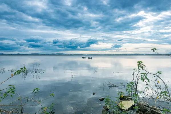 Kabini 'nin sakin, yansıtıcı suları, canlı yeşil yaprakları ve bulutlu gökyüzü ile sakin bir atmosfer yaratıyor..