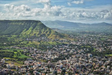 Satara, Maharashtra 'daki Ajinkyatara Kalesi' nden canlı hava manzarası, yemyeşil vadiler, yayılan bir kasaba manzarası ve parçalı bulutlu bir günde uzak tepeler ile çevrili..