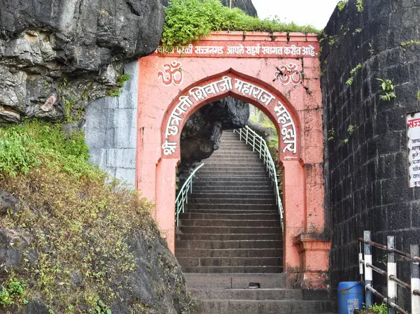 Sajjangad Kalesi 'nin tarihi girişinde Satara, Maharashtra, Hindistan' ın Batı Ghatları 'nda taş basamaklar, canlı yeşillik ve antik mimari yer alıyor..