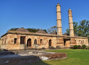 Jami Mescidi, Champaner, Gujarat. Karmaşık taş mimarisi, ikiz minareler ve temiz mavi gökyüzünün altında koridorlarla çevrili sakin bir avlu ile kuzey girişini sergiliyorlar..