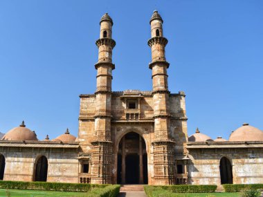 Jami Mescidi 'nin Champaner, Gujarat' taki tarihi girişi, karmaşık mimari detaylar, ikiz minareler ve açık mavi gökyüzünün altında büyük kemerli bir geçit içeriyor..