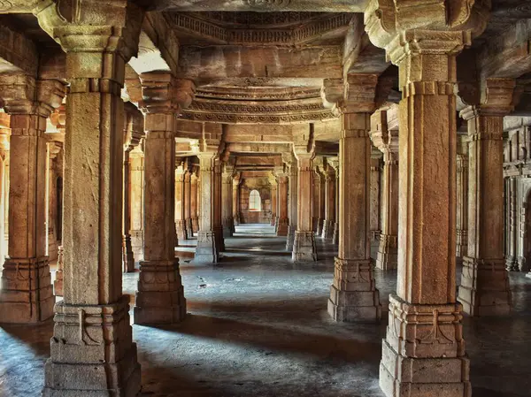 Champaner, Gujarat 'taki Saher-ki-Mescidi' nin karmaşık biçimde oyulmuş taş sütunları, zamansız mimari ve yumuşak doğal ışık altında tarihi işçilik.