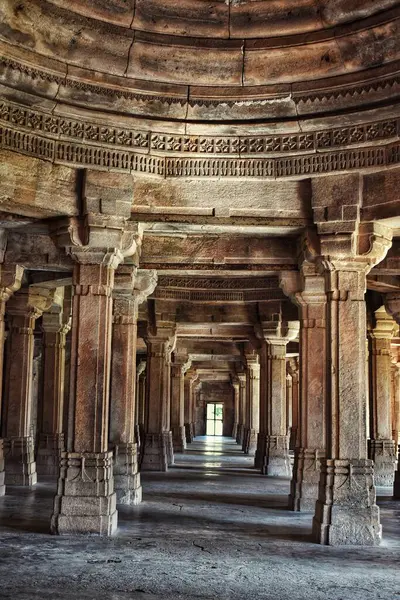 Gujarat, Champaner 'deki Saher-ki-Mescidi' nin simetrik taş sütunları doğal ışık altında karmaşık oymalarla tarihi Hint-İslam mimarisini sergiliyor..