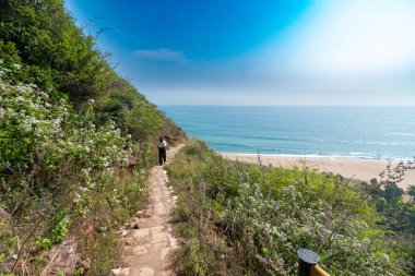 Bereketli yeşillik ve çiçek açan çalılarla dolu sakin bir tepe yolu Yarada Sahili 'nin nefes kesen manzarasına ve berrak mavi gökyüzünün altındaki parıldayan okyanusa yol açar..