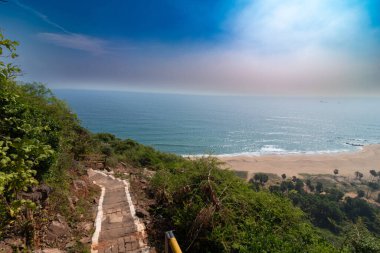 Yeşilliklerle çevrili taştan bir patika Yarada Sahili 'ne çıkıyor. Visakhapatnam' da berrak bir gökyüzünün altında engin okyanusu huzurlu bir şekilde görüyor..