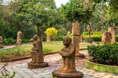 Kailasagiri 'de, Visakhapatnam' da, Andhra Pradesh 'te gün ışığında yeşillik, ağaçlar ve patikalarla çevrili huzurlu bir bahçeye yerleştirilmiş taş heykeller..