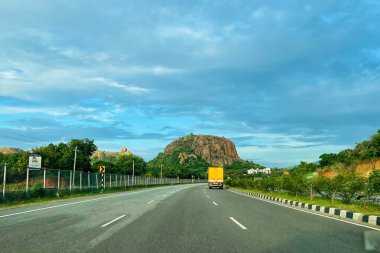 Bangalore ve Mysore arasında Ramnagara 'nın yeşil ve kayalık tepeleriyle çevrili boş bir ulusal otoyol. Parlak, parçalı, mavi bir gökyüzü altında..