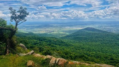 Geniş yeşil vadinin panoramik bir görüntüsü ve BR Hills Tiger Reserve 'den yakalanan yoğun ormanlar, kayan tepeler, dağınık ağaçlar ve dağınık mavi bulutlu canlı bir gökyüzü..